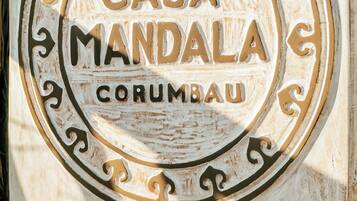 Un panneau en bois portant l’inscription « CASA MANDALA CORUMBAU » et un numéro de téléphone.