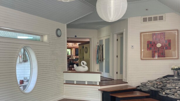 Een modern binnenzwembad met houten terrassen, een zwanenbeeld en een ingelijst kunstwerk aan de muur.