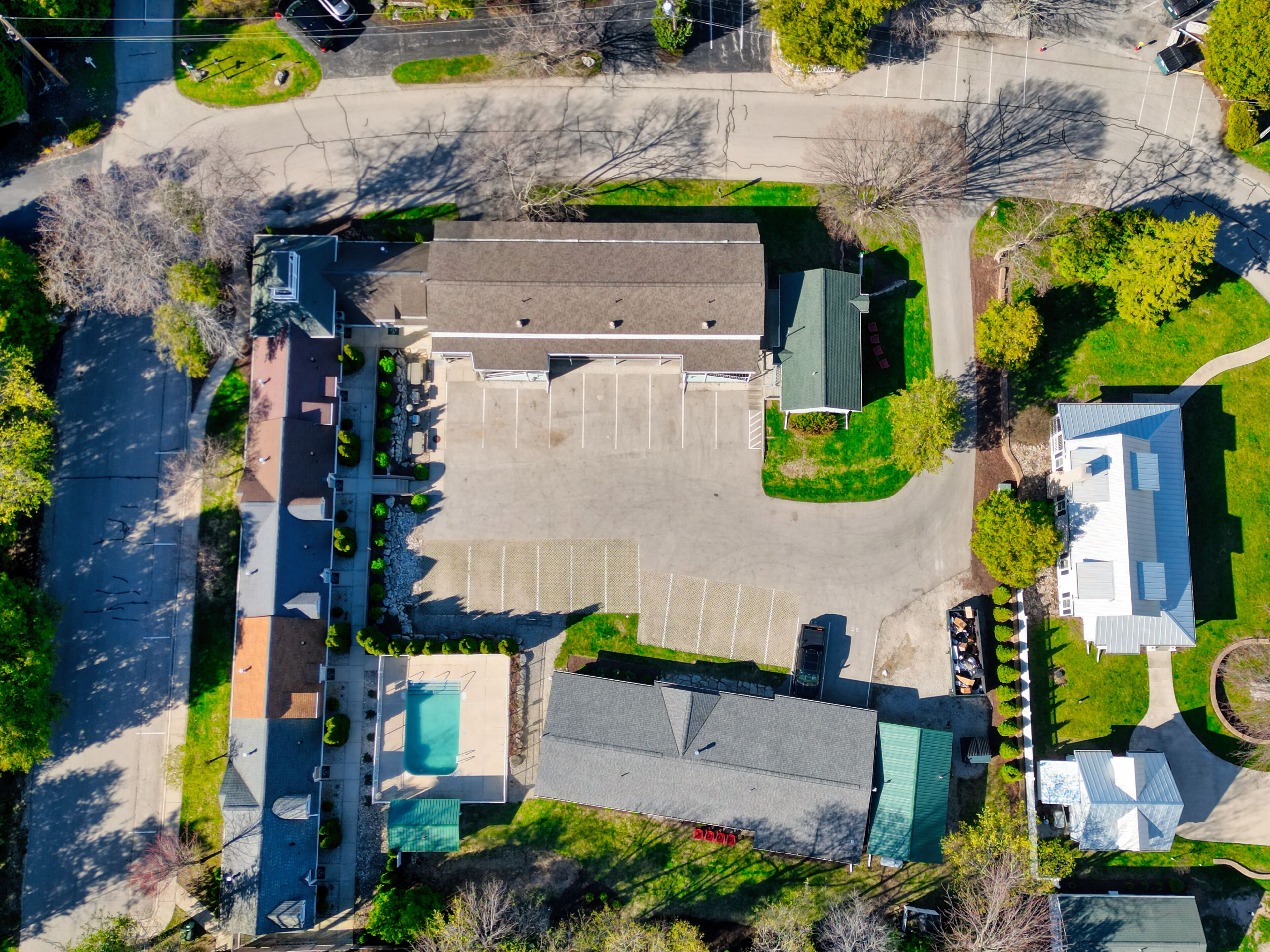 Vue aérienne d’un quartier résidentiel avec un grand parking, une piscine et une maison dotée d’un toit végétalisé.