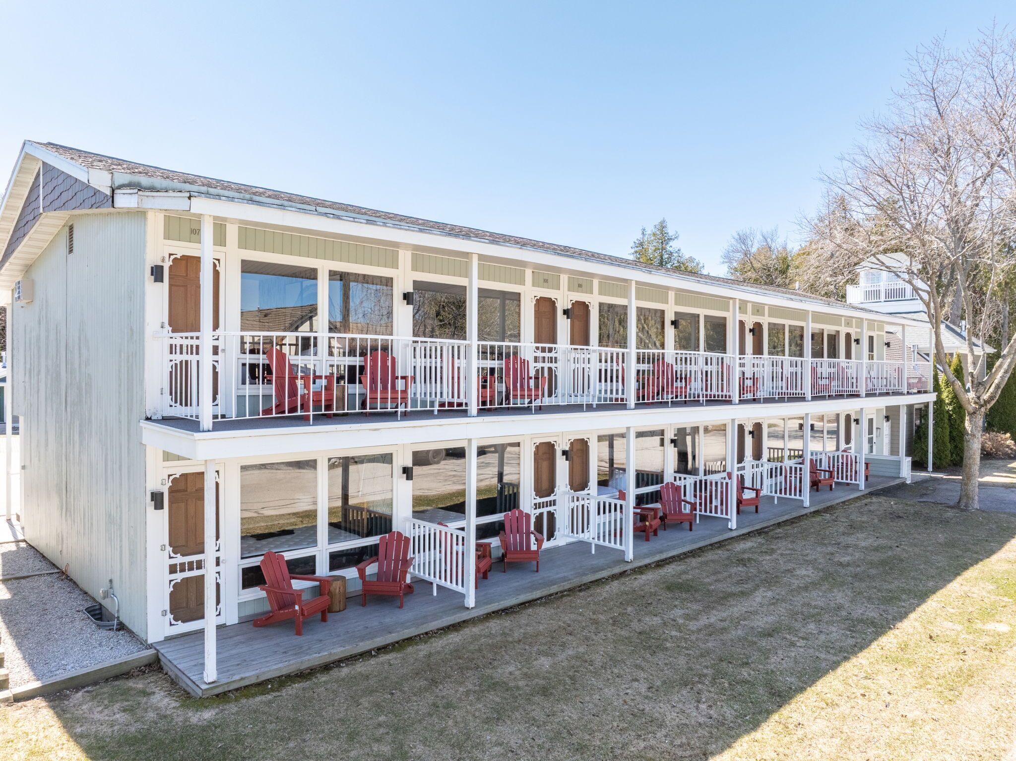 A two-story building with multiple balconies, each with red Adirondack chairs.