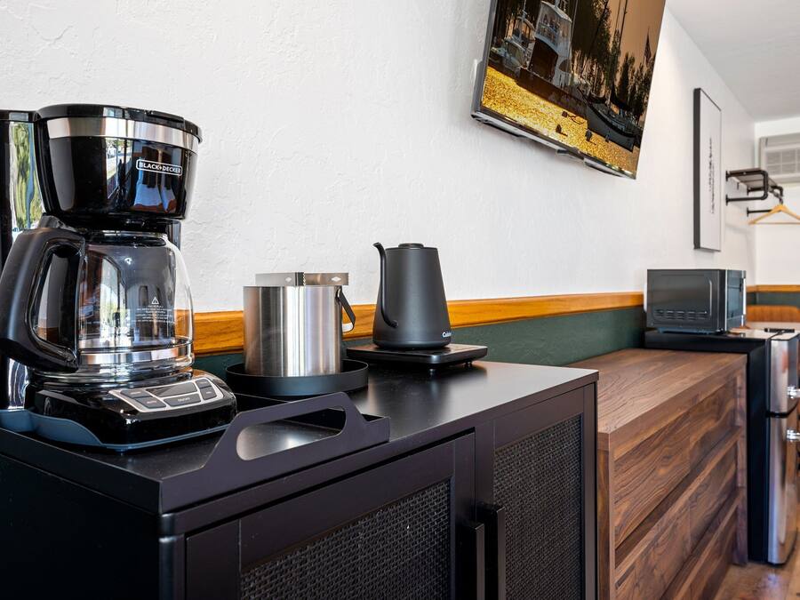 Een kitchenette met een koffiezetapparaat, waterkoker en magnetron.