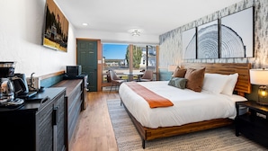 A hotel room with a large bed, a desk with a coffee maker, a TV, and a view of the outdoors.