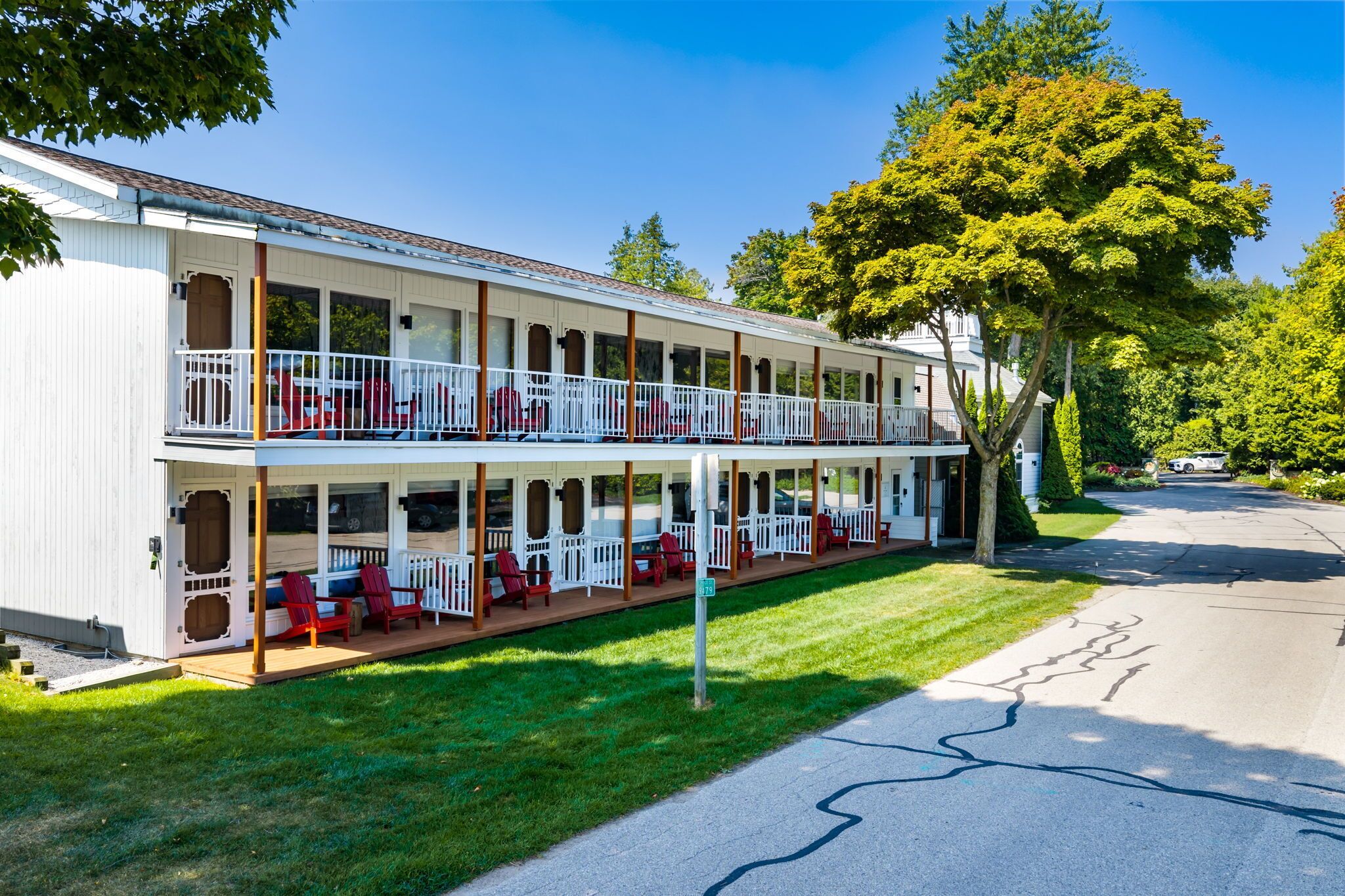 Un motel de dos pisos con un porche cubierto y asientos exteriores.