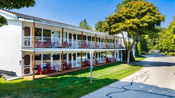 Un motel de dos pisos con un porche cubierto y asientos exteriores.
