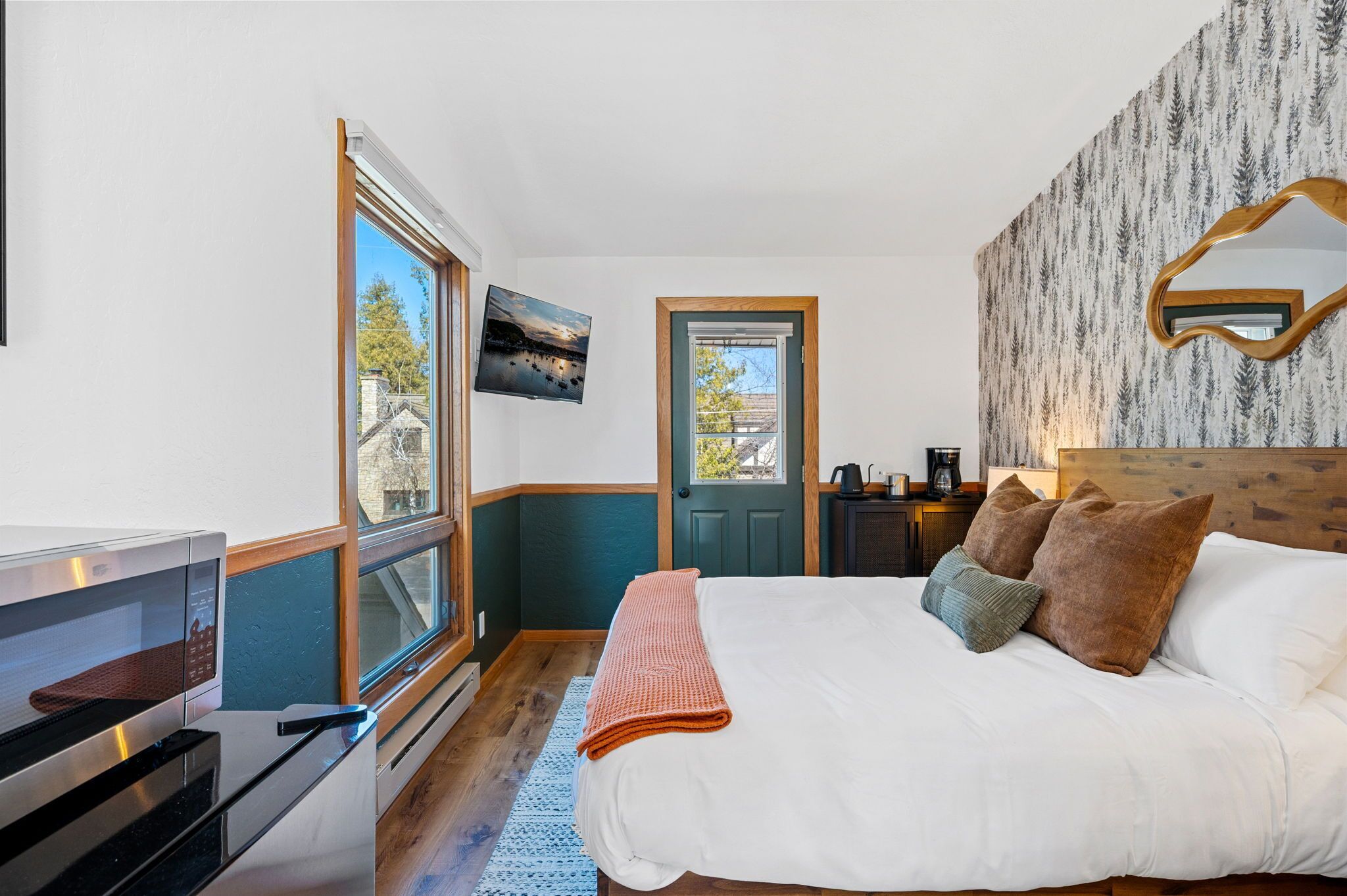 Une chambre à coucher comprenant un lit, un téléviseur, un four à micro-ondes et une porte donnant sur une salle de bain.