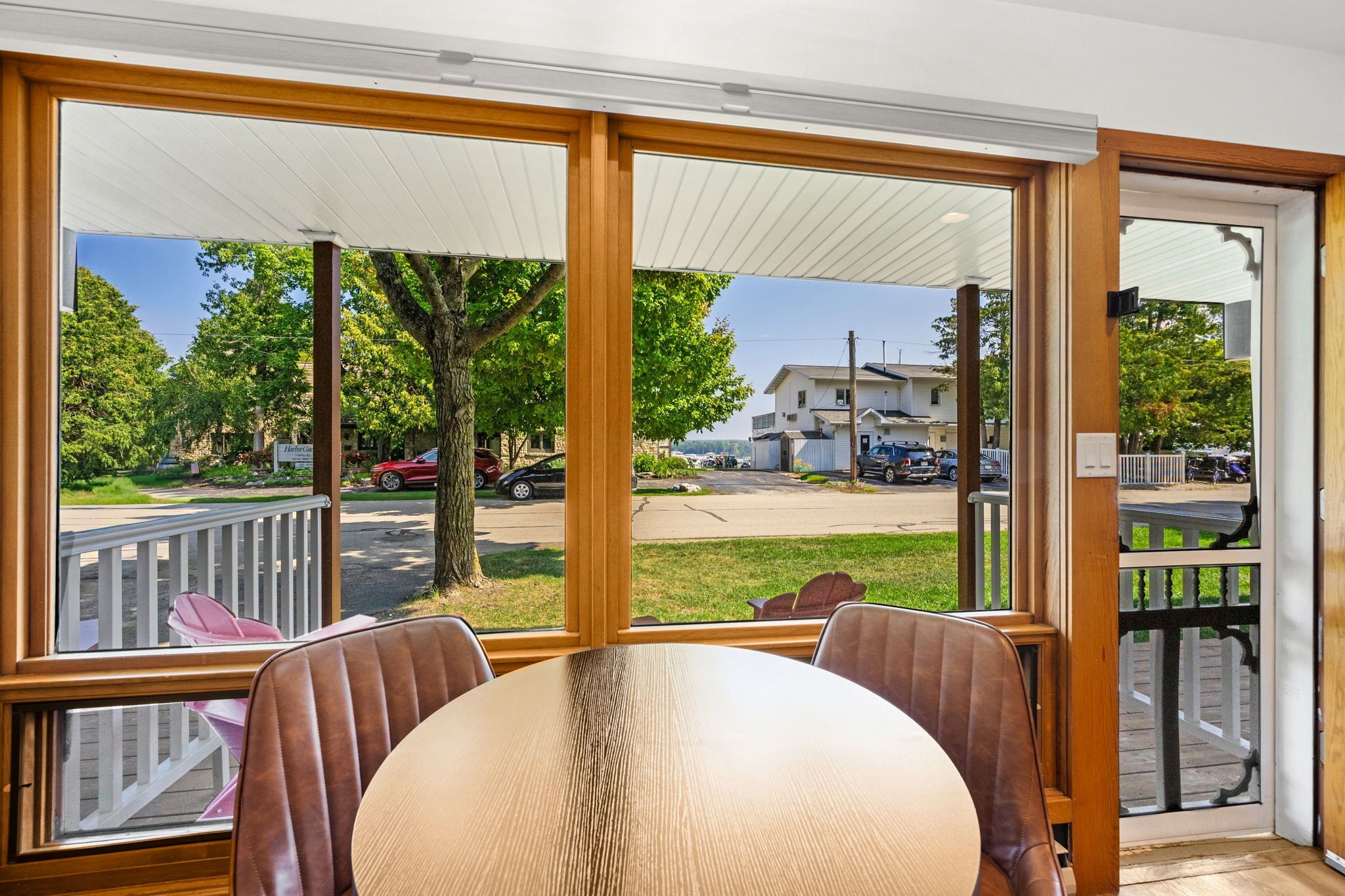 A dining area with a table and chairs, large windows with a view of a street and parked cars.