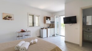 A bedroom with a bed, a desk, a TV, and a bathroom. - Villa Dei Tre Colli - Noto (Noto)