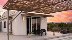 A modern outdoor patio with a pool, a covered seating area, and a view of the landscape. - Villa Dei Tre Colli - Noto (Noto)