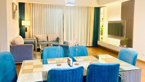 A modern hotel room with a dining area, a sofa set, a TV, and a large window with curtains. - Monaara Leisure colombo 03 (Colombo)