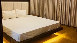A modern bedroom with a large bed, wooden headboard, and a light fixture above the bed. - Monaara Leisure colombo 03 (Colombo)