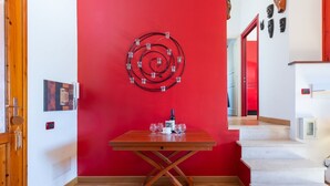 A modern interior with a red accent wall, a wooden table with wine glasses, and a spiral light fixture.