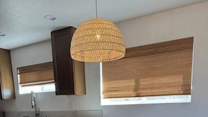 Une cuisine moderne avec des meubles de couleur sombre, un plan de travail blanc et un luminaire suspendu.