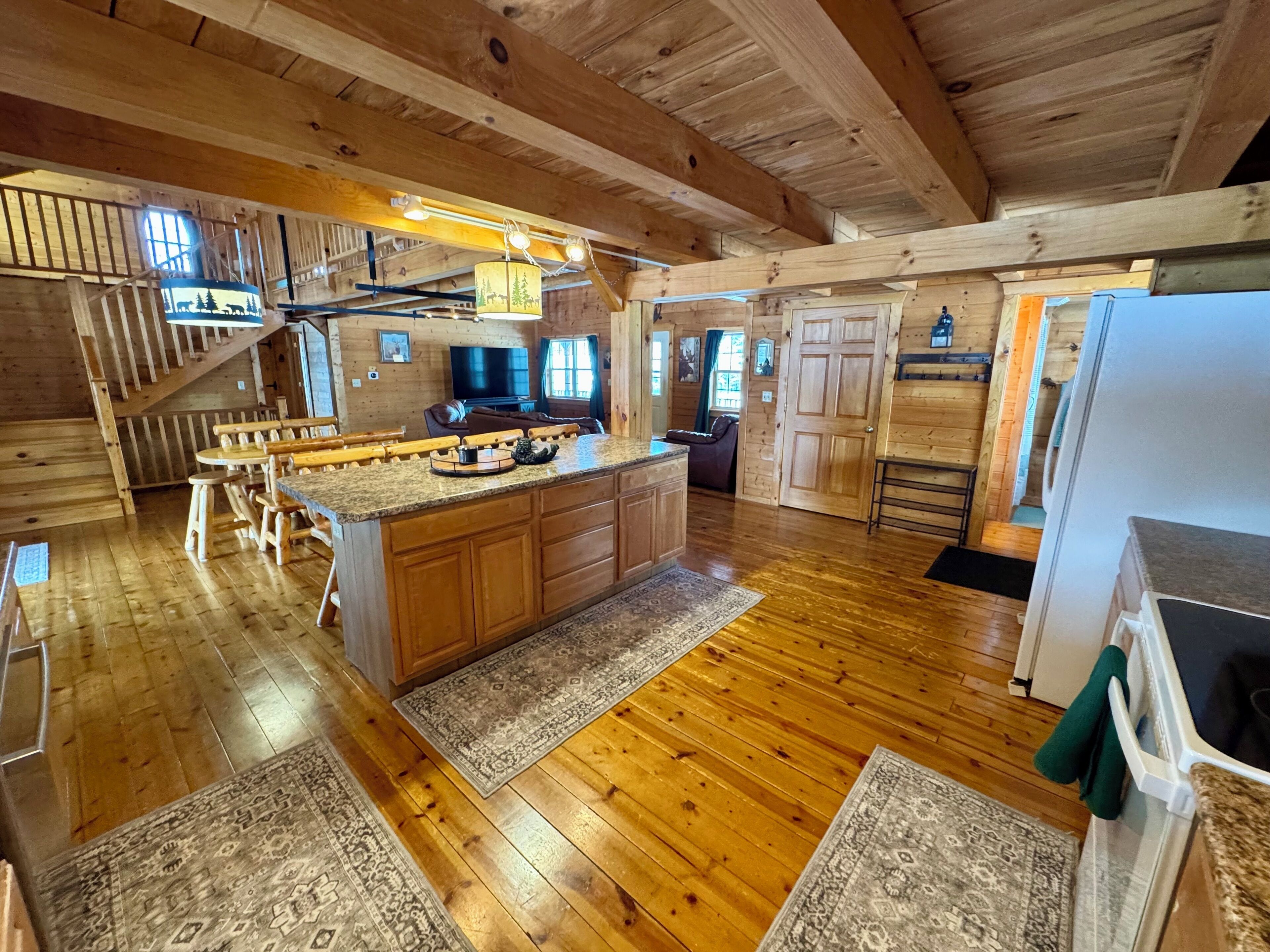 Une cuisine spacieuse dotée de planchers en bois, d’un îlot central et d’un coin repas avec des bancs.