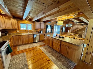 A wooden cabin-style kitchen with granite countertops, wooden cabinets, a dishwasher, and a built-in stove.