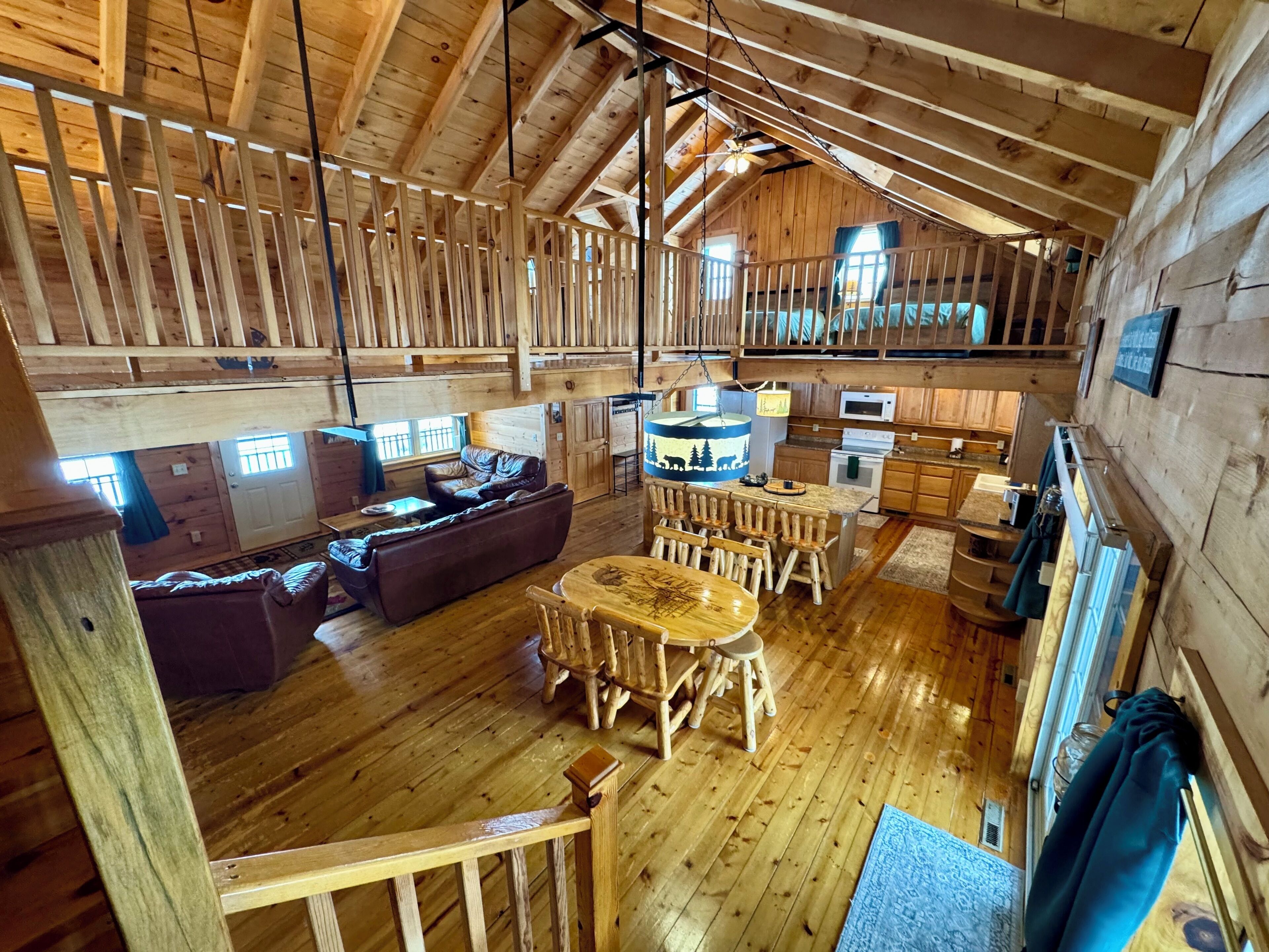 Une cabine spacieuse avec un plafond haut, un plancher en bois, un coin repas avec des tabourets, un canapé et un coin cuisine équipé d’un four à micro-ondes et d’une cuisinière.