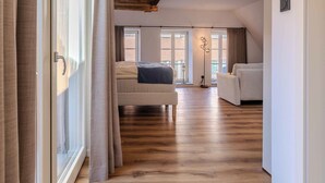 Une pièce spacieuse avec un grand lit, un canapé et une lampe sur pied.