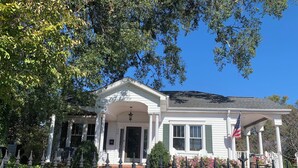 A white building with a porch, a flag, and a brick pathway. - Beautiful,comfortable, safe suite with private entrance. (Dallas)