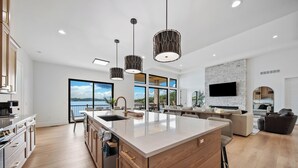 A modern kitchen with a large island, pendant lighting, and a view to the outdoors. - The Rosco! Main Channel! Private Pool, Spa, Mini Golf, Gm Rm! Sleeps 32! (Lake Ozark)