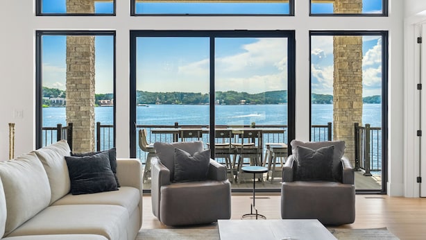 A spacious living area with a large window overlooking a body of water, furnished with a sofa and two armchairs. - The Rosco! Main Channel! Private Pool, Spa, Mini Golf, Gm Rm! Sleeps 32! (Lake Ozark)