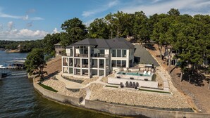 A modern two-story house with a large glass facade, a swimming pool, and a dock. - The Rosco! Main Channel! Private Pool, Spa, Mini Golf, Gm Rm! Sleeps 32! (Lake Ozark)
