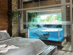 A bedroom with a large window overlooking a swimming pool. - Roteiros Adorai (Piedade)