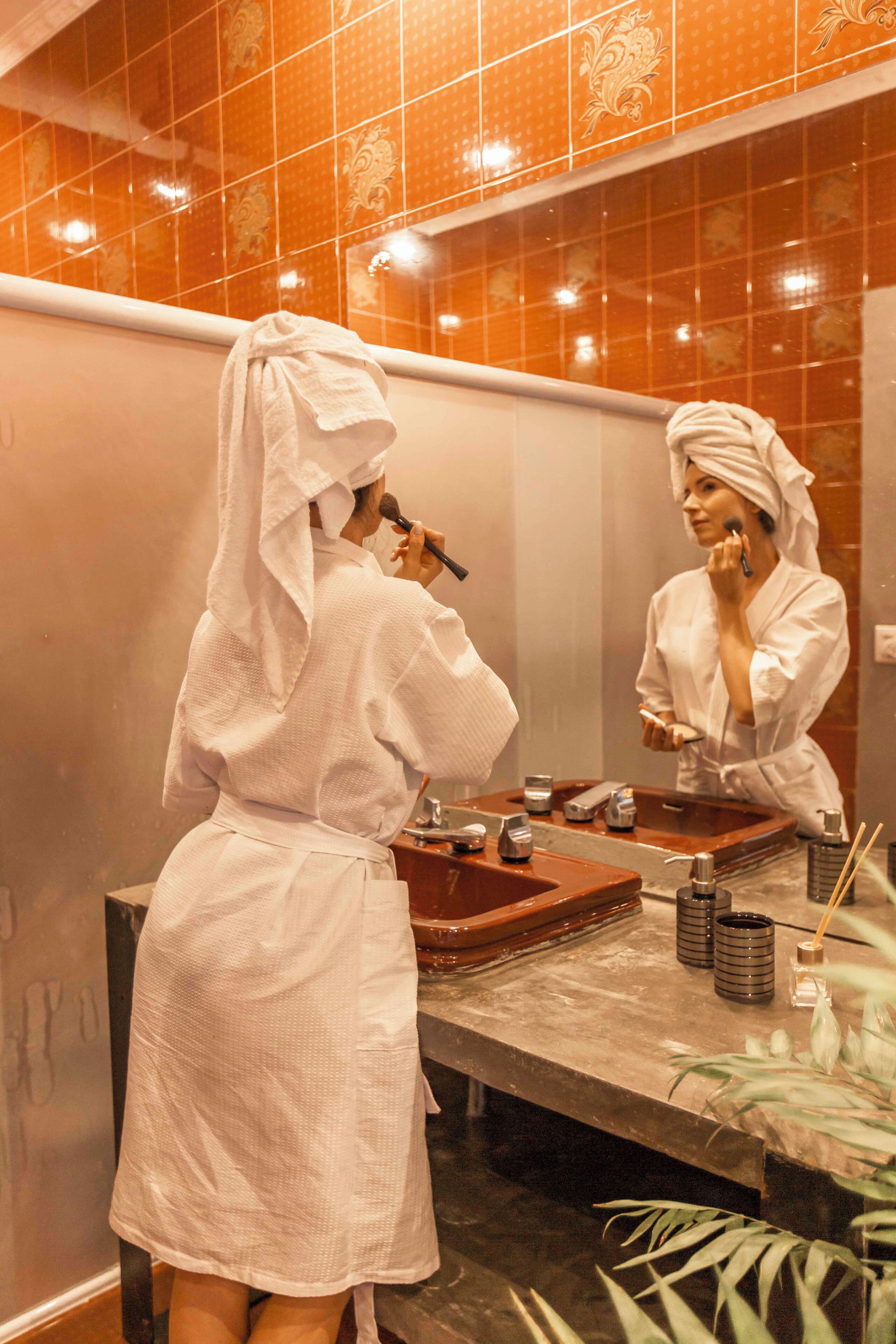 A bathroom with orange tiles, a wooden vanity, and a mirror.
