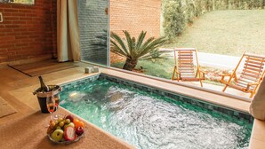 A swimming pool with a glass enclosure, wooden deck chairs, and a fruit bowl on the side. - Roteiros Adorai (Piedade)