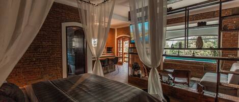 Un dormitorio con una cama grande, un escritorio de madera y vista a una piscina a través de una ventana.