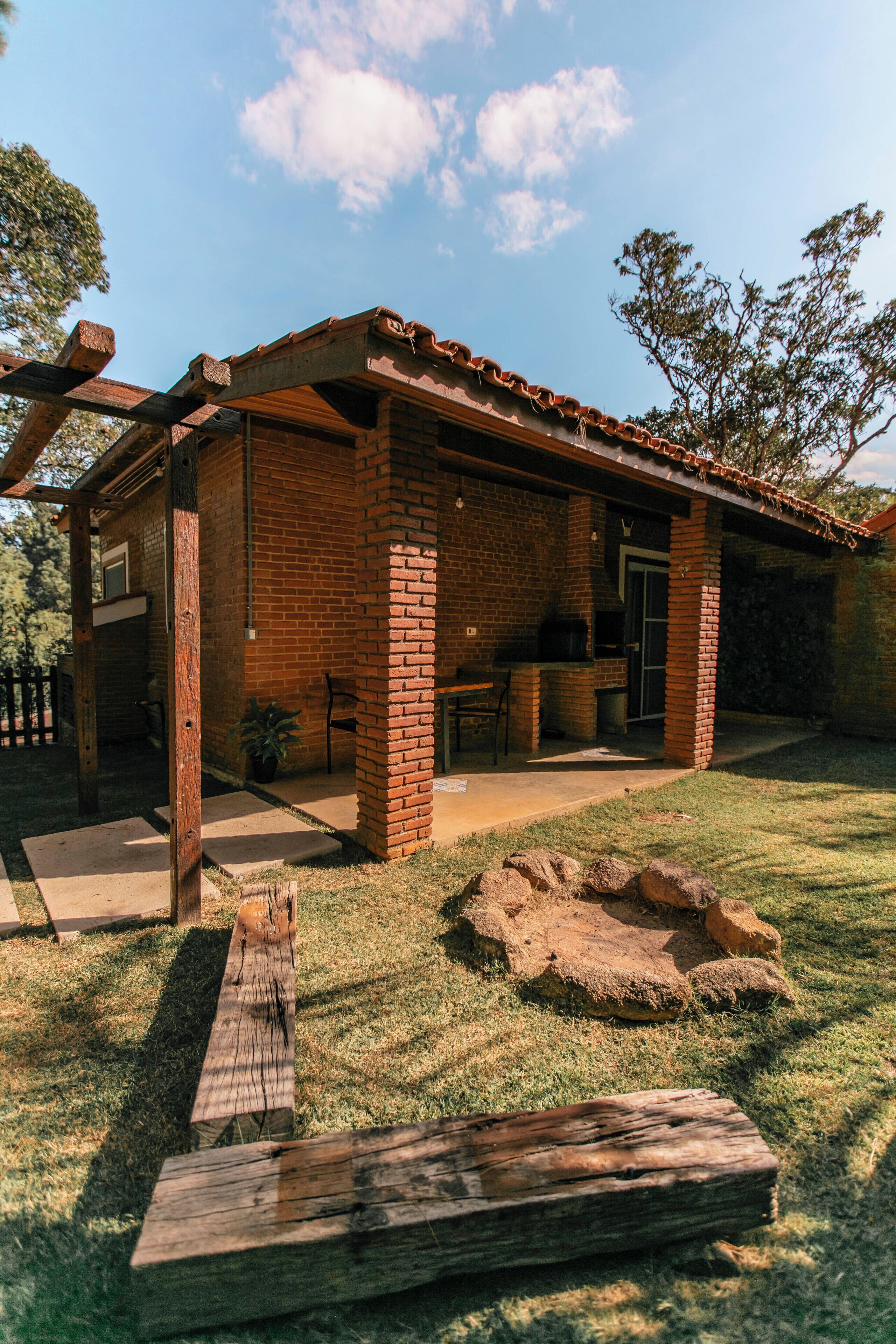 A brick house with a patio, outdoor seating, and a grill area.