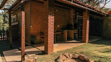 A brick house with a patio, outdoor seating, and a grill area.