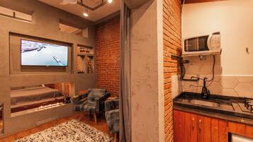 A modern living room with a fireplace, comfortable seating, a flat-screen TV, and a kitchen area with a microwave.