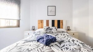 A bedroom with a bed, two bedside tables, a wall art piece, and a window.