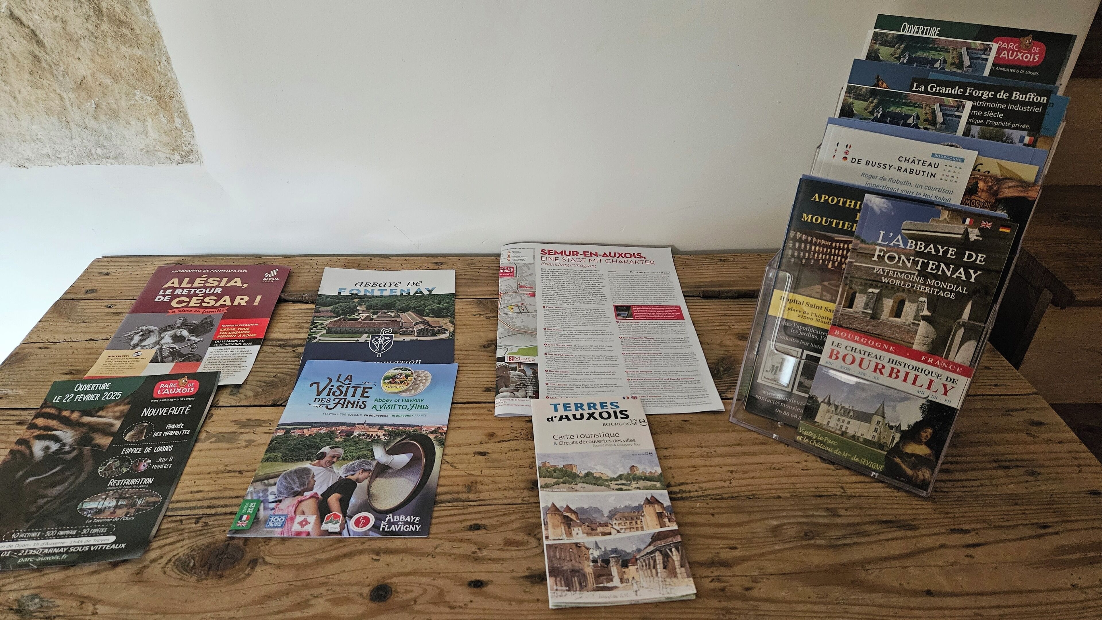 A collection of brochures and maps on a wooden table, featuring various destinations and attractions.