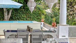 Un espace extérieur aménagé avec des meubles en osier, un tapis à motifs et des plantes décoratives.