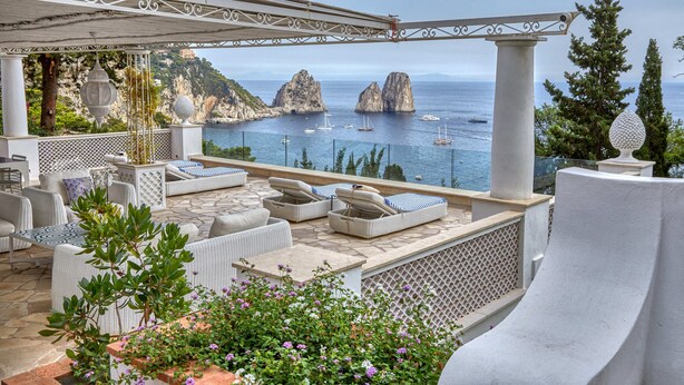 Une terrasse avec des places assises à l’extérieur, une vue sur la mer et des falaises rocheuses.