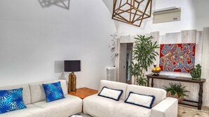 Un salon moderne avec un canapé d’angle, une table basse en verre et un luminaire au design géométrique.