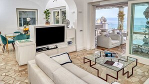 Un salon spacieux doté d’un grand téléviseur, de sièges confortables et offrant une vue sur la mer.