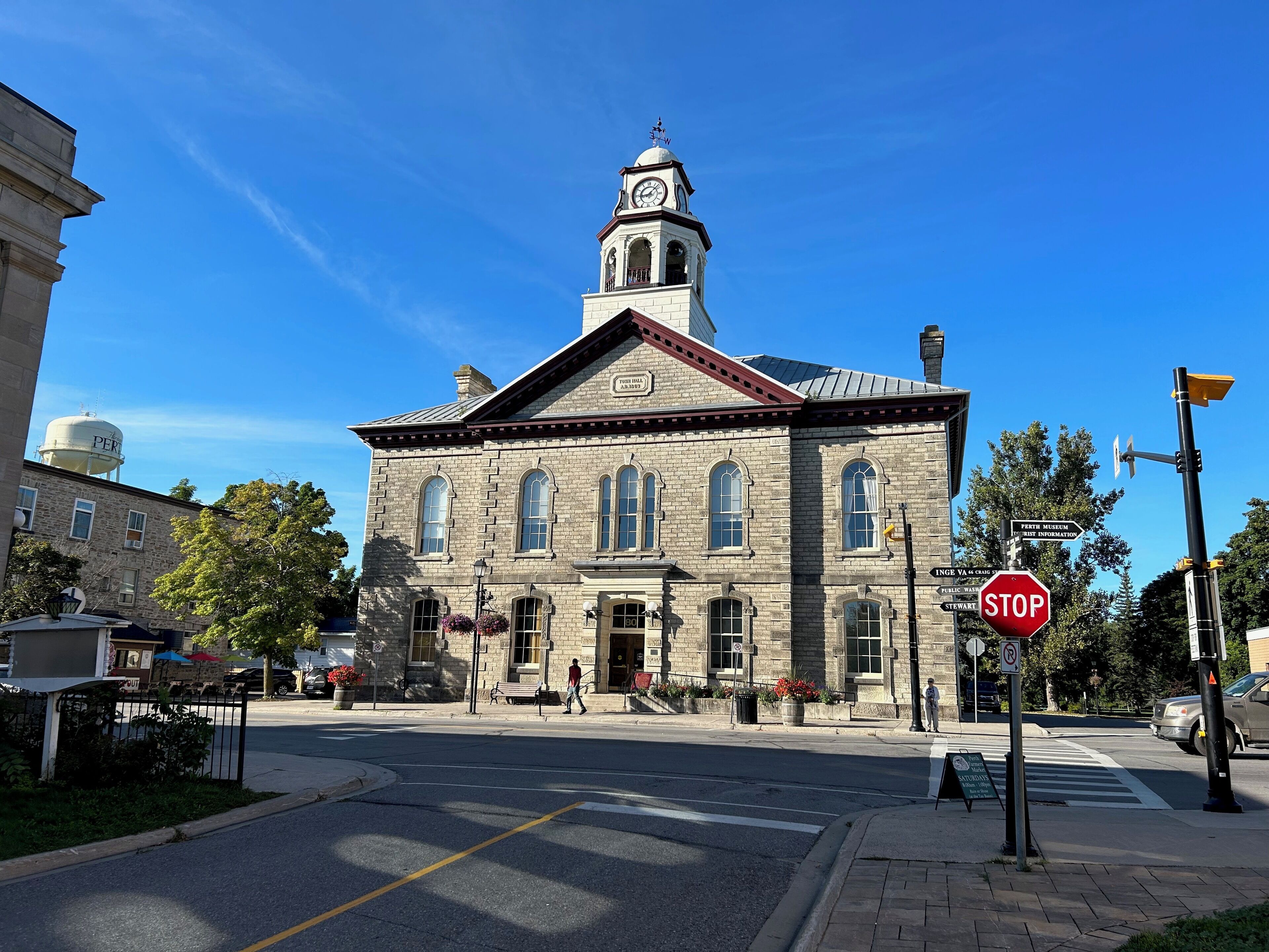 A historic stone building with a clock tower, a stop sign, and a pedestrian crossing.