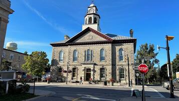 A historic stone building with a clock tower, a stop sign, and a pedestrian crossing.