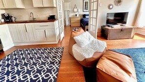 A compact living space with a kitchenette, a sofa, a television, and a patterned rug.
