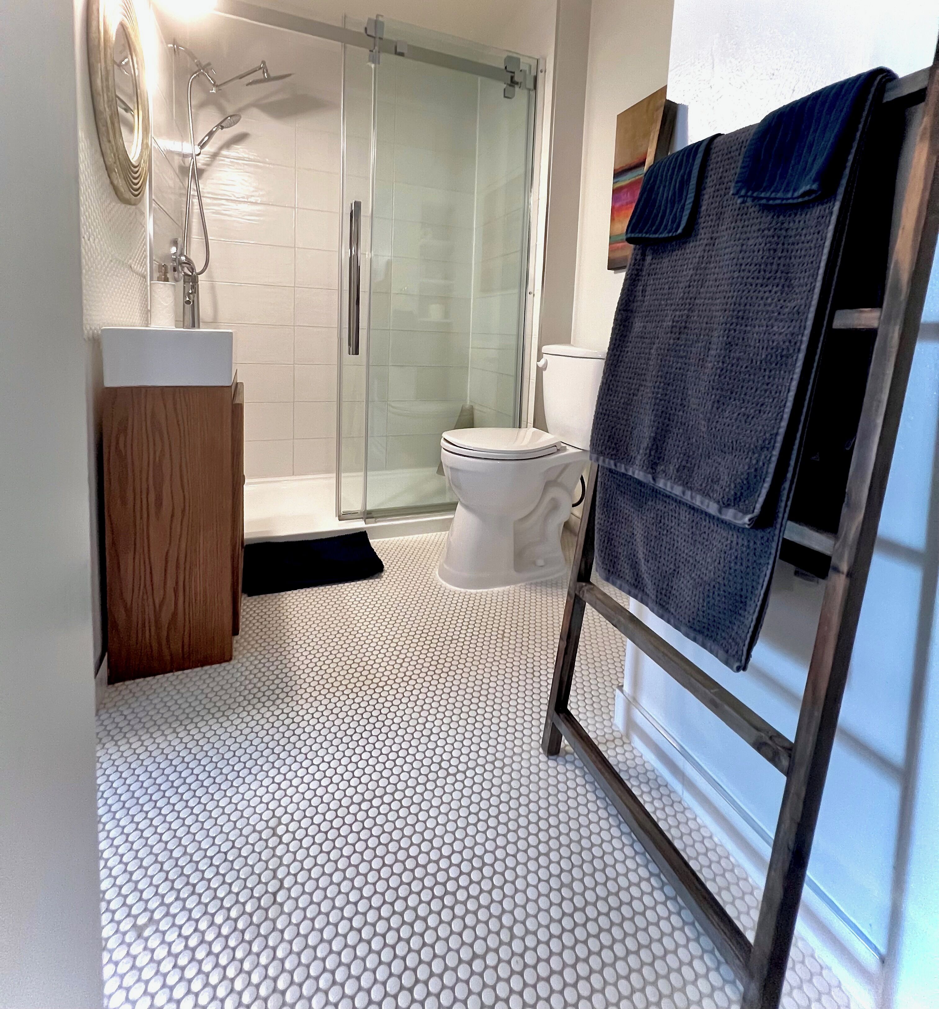 A bathroom with a glass shower enclosure, a toilet, a sink, and a towel rack.