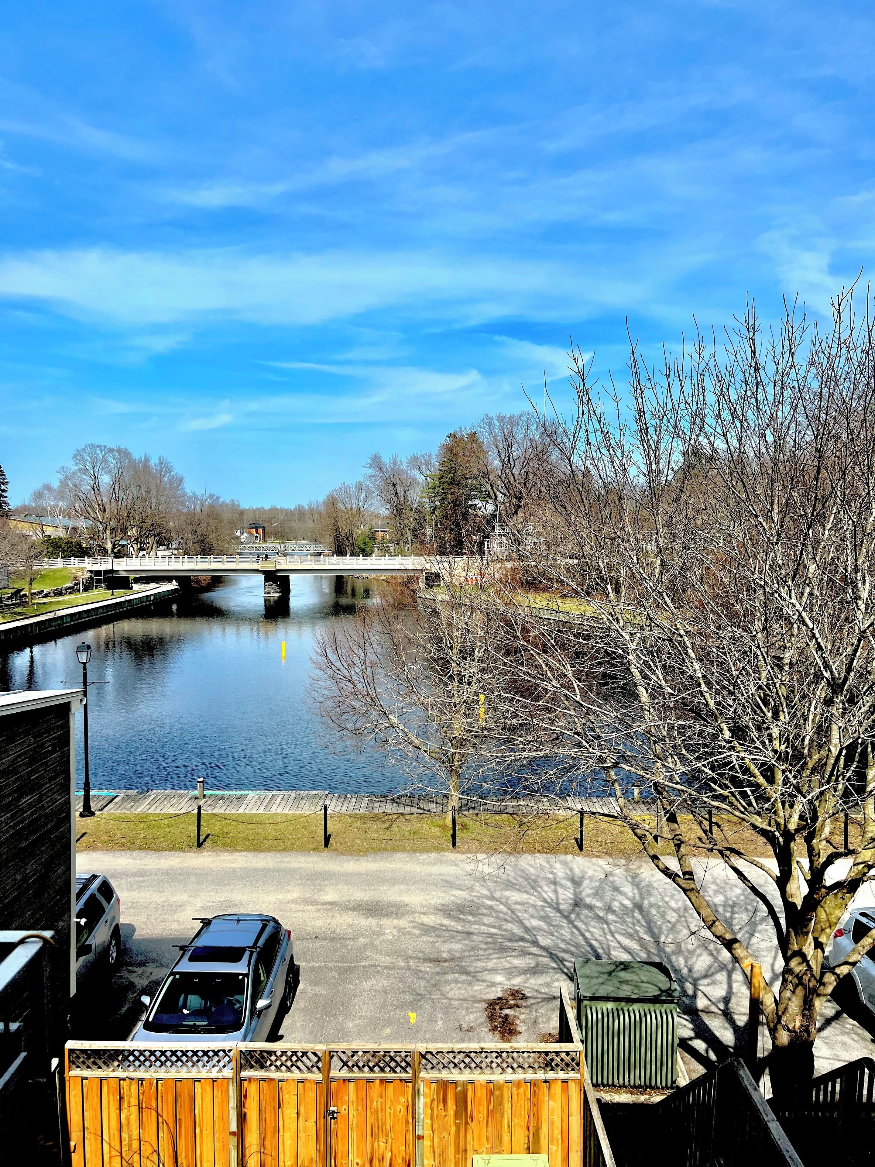 Vista di un fiume con un ponte, un'area di parcheggio e una recinzione in legno.