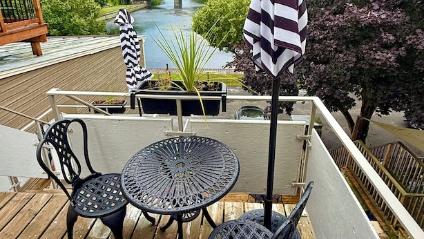 A deck with two tables and chairs, overlooking a river and surrounded by greenery. - Designer Maisonnette with Stunning Tay Basin and Fountain View (Perth)