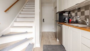 A staircase leading to a door, a kitchen with white cabinets and a wooden countertop, and a grey rug on the floor. - Designer Maisonnette with Stunning Tay Basin and Fountain View (Perth)