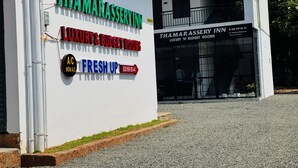 Ein Gebäude mit Hinweisschildern für Thamarassery Inn, das luxuriöse und preisgünstige Zimmer anbietet.