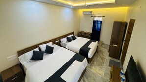 Ein Hotelzimmer mit zwei Betten, einem Schreibtisch, einem Kleiderschrank und einem Deckenventilator.