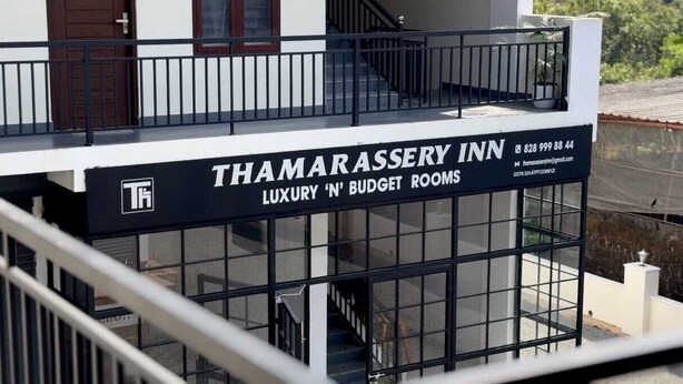 Ein Hotelschild mit der Aufschrift "Thamarassery Inn" und "Luxus- und Budgetzimmer", das die verfügbaren Unterkunftsarten anzeigt.