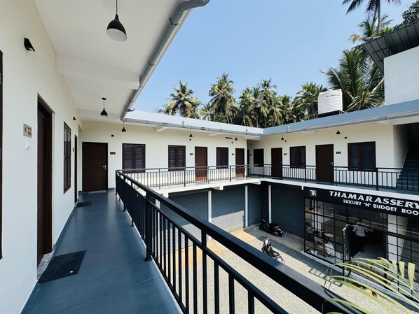 A building with multiple rooms, a balcony, and a sign for 'Thamarassery Luxury 'N' Budget Rooftop'. - Thamarassery INN Luxury and Budget Rooms (Thamarassery)