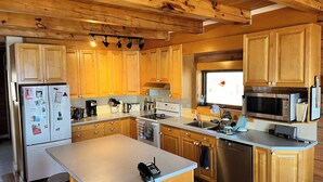 Una cocina con armarios de madera, un refrigerador, estufa, microondas y lavavajillas.