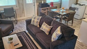 Un espacio habitable compacto con sofá, una mesa de comedor y una zona de cocina.